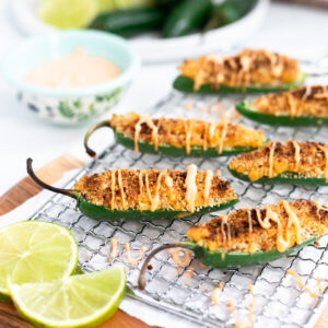 close up of vegan jalapeno poppers with Siracha Aioli and lime