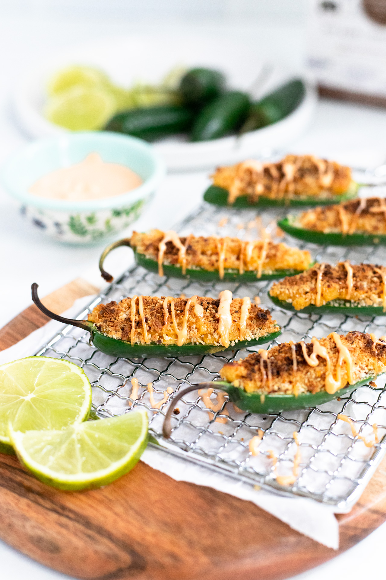 close up of vegan jalapeno poppers with Siracha Aioli and lime